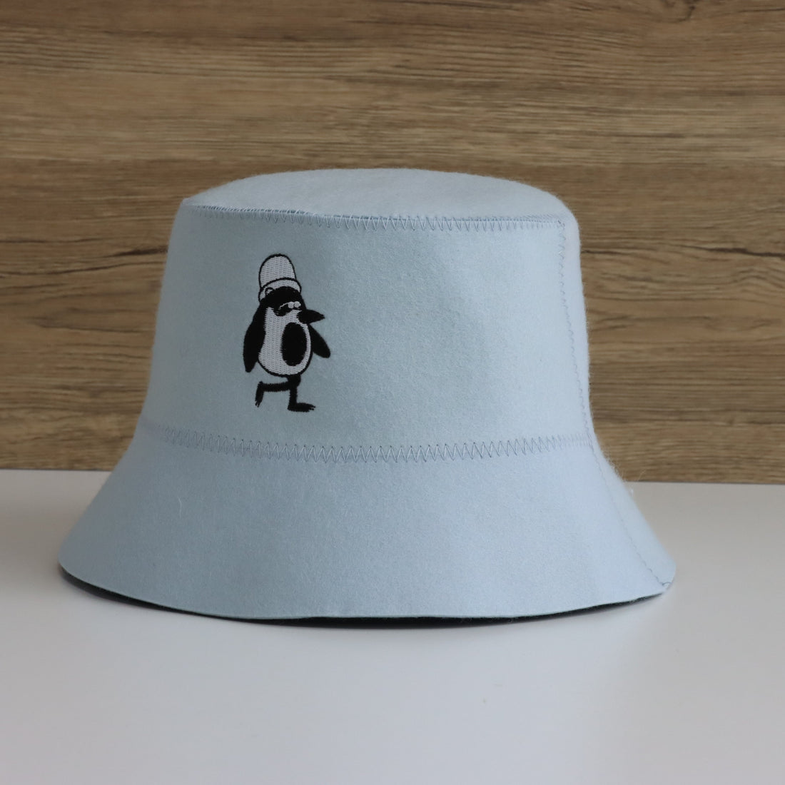 Close-up of Vanya the Penguin embroidery on the Sky colorway Schvitzin Starter merino wool sauna hat