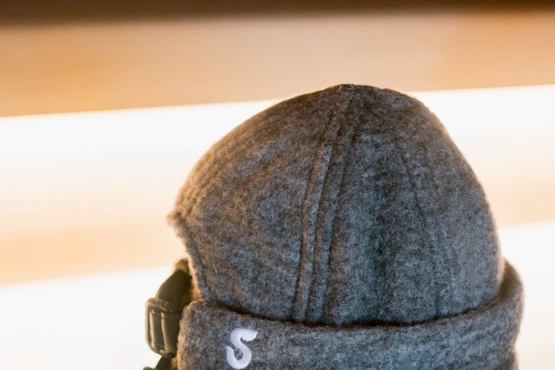 Back view of a charcoal gray Schvitzin merino wool felt sauna hat, showing the structured seam detail and black leather adjustable buckle strap