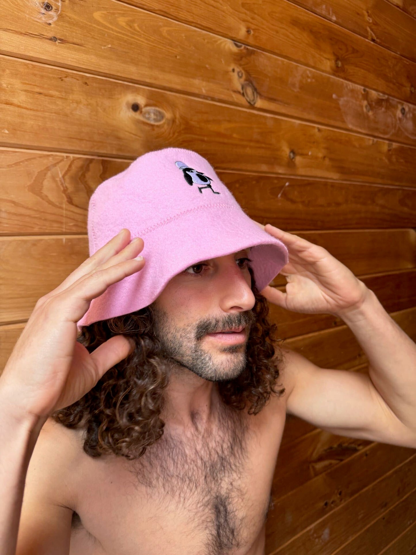 Schvitzin Starter sauna hat in Rose, 100% merino wool bucket hat with Vanya penguin embroidery, worn in sauna, Brooklyn NY