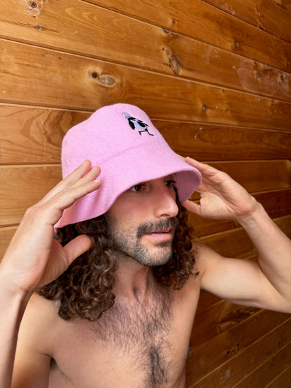Schvitzin Starter sauna hat in Rose, 100% merino wool bucket hat with Vanya penguin embroidery, worn in sauna, Brooklyn NY