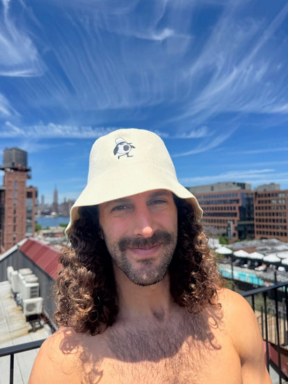 Person wearing the Natural Cream colorway Schvitzin Starter merino wool sauna hat on a Brooklyn rooftop with the NYC skyline in the background