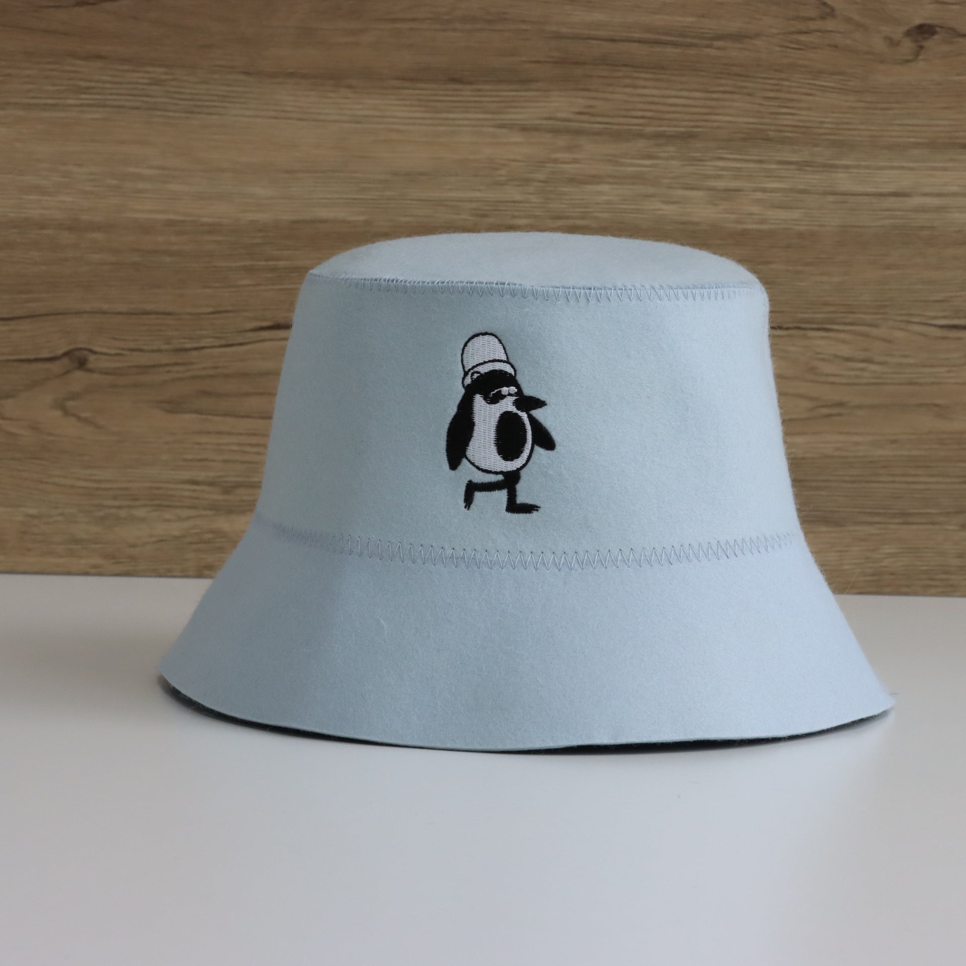 Schvitzin Starter merino wool sauna hat in Sky with Vanya the Penguin embroidery on the front, product shot on white surface
