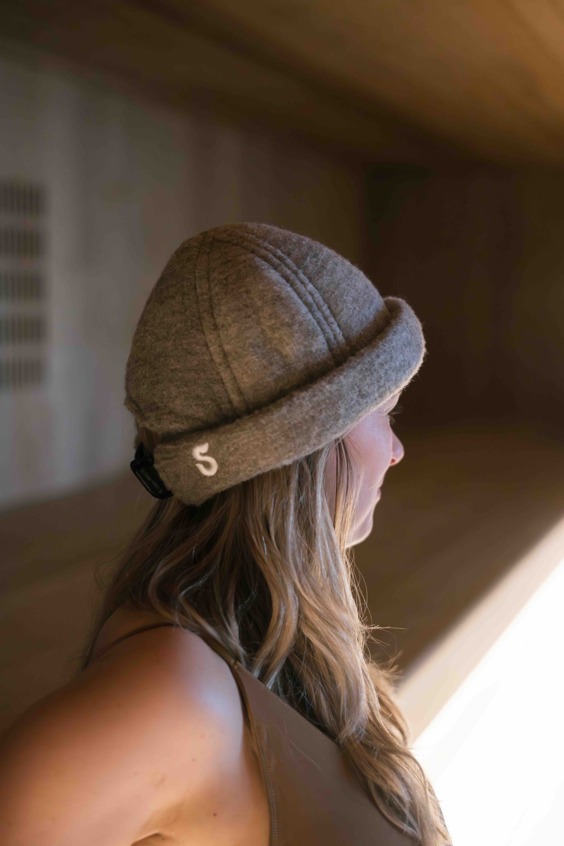 Schvitzin premium merino wool sauna hat worn by woman, adjustable fit, S logo detail