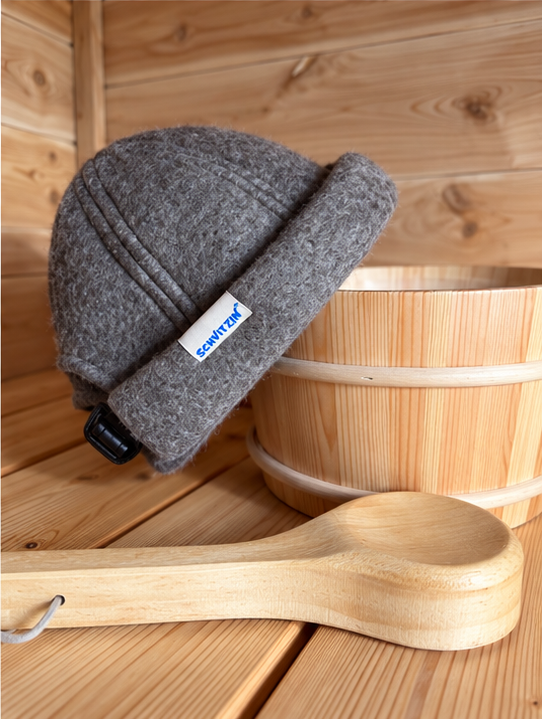 Schvitzin woven-label merino wool sauna hat beside wooden sauna bucket and ladle